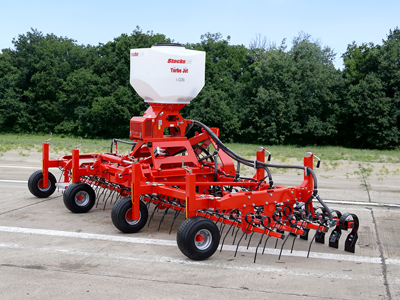 Yard image of side of HE-VA Grass Combi fitted with Stocks Ag Turbo Jet 8 Applicator, hedge background